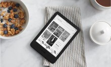 a kindle e-reader sits in a kitchen table next to a bowl of cereal