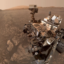 The dust-covered Curiosity rover exploring the Martian surface.