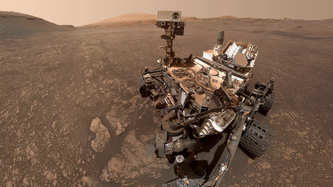 The dust-covered Curiosity rover exploring the Martian surface.