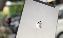 The Apple iPad 6 in a silver color held up in an outdoor setting, with the background blurred