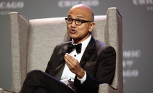 Microsoft CEO Satya Nadella speaking in a black tail coat with bowtie while he sits in a chair.