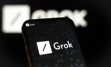 A phone displaying the Grok xAI logo, which is a white box with a black slash across it. 