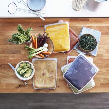 An assortment of stasher bags filled with soups, smoothies, and more on a kitchen counter.