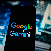 A Google Gemini logo is displayed on a smartphone with Artificial Intelligence symbol on the background.