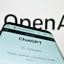 OpenAI logo with ChatGPT app on a phone