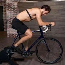 shirtless man wearing chest heart rate monitor on exercise bike