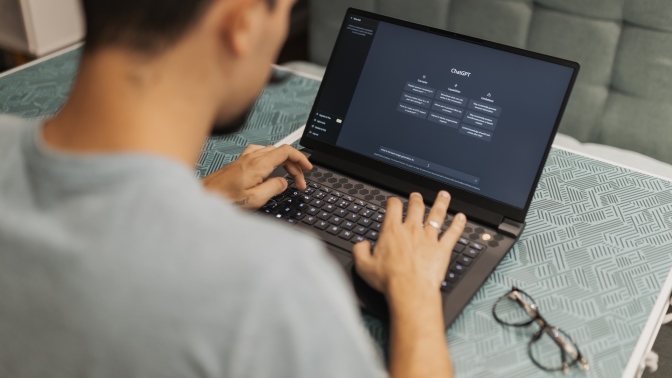 A person sits at a laptop with ChatGPT on the screen.