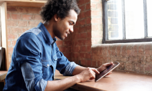 man sitting at desk using ipad