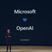 Microsoft CEO Satya Nadella in front of a screen that says Microsoft with a heart below and OpenAI