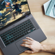 a top-down view of a man playing "the witcher 3" on a Acer Chromebook 516 GE at a wooden desk