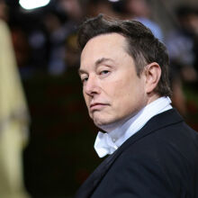 Image of Elon Musk wearing a tuxedo looking at the camera from over his shoulder