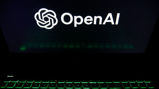 The OpenAI logo is being displayed on a laptop screen with a glowing green keyboard 