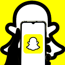 A hand holding a smartphone with the Snapchat logo visible. 