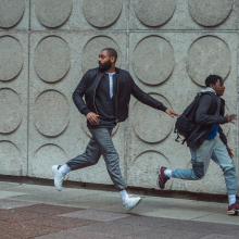 A man and a boy run down a street.