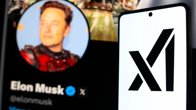 the xAI logo seen displayed on a smartphone with the official profile of Elon Musk, of the social network X in the background