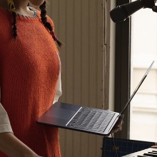 person holding m2 macbook air in front of piano