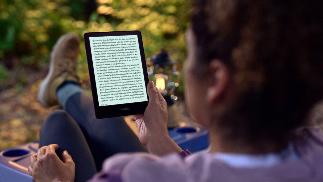 Person reading Kindle while sitting outside in hiking gear