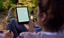 Person reading Kindle while sitting outside in hiking gear