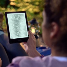 Person reading Kindle while sitting outside in hiking gear