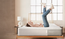 Side-shot of a woman laying on a bare mattress, feet in the air