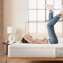 Side-shot of a woman laying on a bare mattress, feet in the air