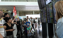 Passengers look at a screen displaying delayed flights at Barcelona Airport on July 19, 2024 in Barcelona, Spain. 