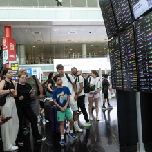 Passengers look at a screen displaying delayed flights at Barcelona Airport on July 19, 2024 in Barcelona, Spain. 