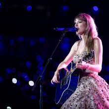 Taylor Swift performing with her guitar on stage at The Eras Tour