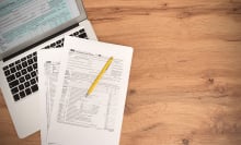 Tax paperwork on a table next to a laptop.