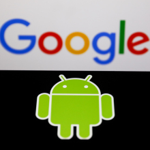 A phone displays the Android logo in front of the Google homepage.