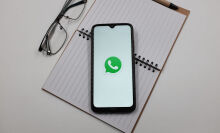 WhatsApp logo on phone screen on top of notepad