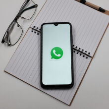 WhatsApp logo on phone screen on top of notepad