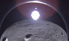 A transmission from Intuitive Machines' Odysseus moon lander showing the crescent Earth near the top of the image, to the left of center.