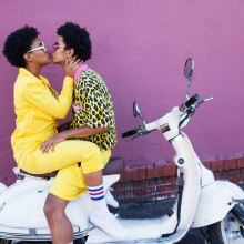 Young couple kissing on the back of a scooter