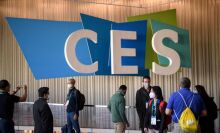 The multicolors CES logo in background while people walk around.