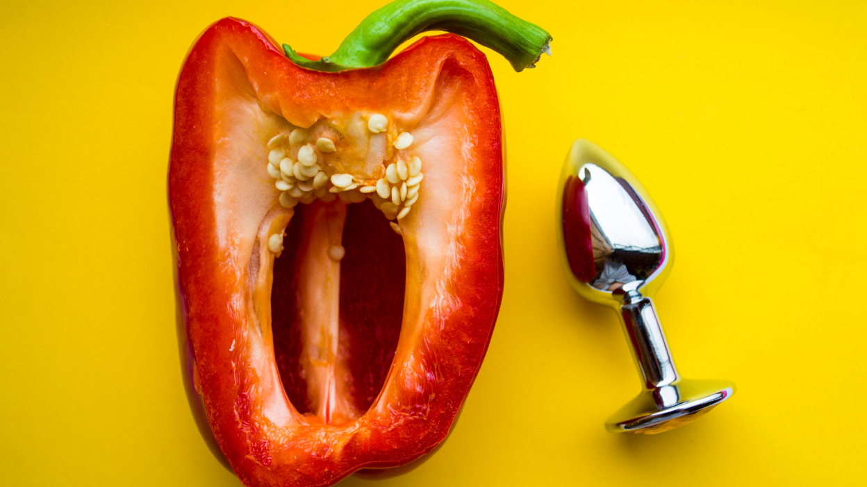 half of a pepper next to a butt plug in front of yellow background