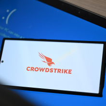 CrowdStrike logo on smartphone on top of Windows blue screen of death