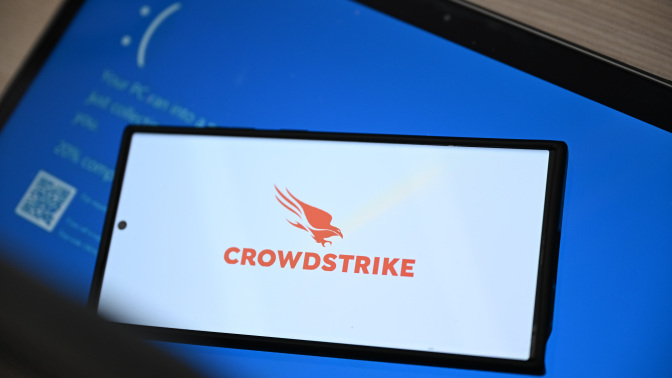 CrowdStrike logo on smartphone on top of Windows blue screen of death