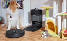 A Roborock robot vacuum cleans up pet hair in a playroom next to a dog
