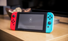 Nintendo Switch console sitting on table with TV in background