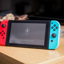 Nintendo Switch console sitting on table with TV in background