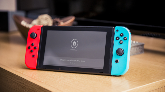 Nintendo Switch console sitting on table with TV in background