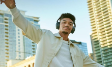 A person wearing Bose QuietComfort headphones in front of a cityscape