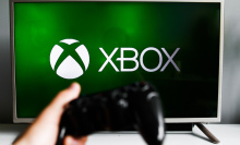 xbox logo on tv with hand holding controller in foreground