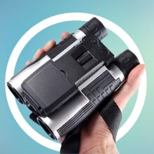 hand holding binoculars over blue background