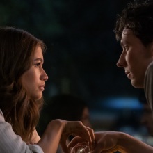 Tashi and Patrick from "Challengers" hold hands over a table.