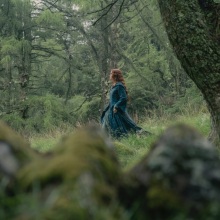 Alicent Hightower walks through the Kingswood in a green dress and cloak.