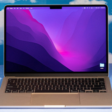 2022 MacBook Air M2 laptop open against a blue backdrop with cloud patterns