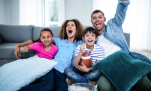 a family cheers while watching a football game from the couch