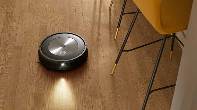 Roomba j7 robot vacuum cleaning hardwood floor with kitchen chair legs in peripherals